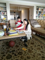 朱小贞和小儿子在客厅里，背后书架为起火点。受访者供图 - News.Sina.com.Cn