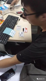 ▲一名工作人员正在检验“兼职人员”的身份证、银行卡、U盾。      视频截图  - News.Sina.com.Cn