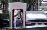 2018年7月11日，北京，一名男子在特斯拉中国总部外为车充电。 - News.Sina.com.Cn
