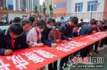 学生们在“爱路护路健康成长”横幅上签名。刘忠俊摄 - Sc.Chinanews.Com.Cn