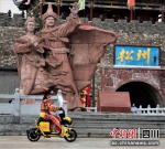 居民骑电单车路过松潘古城。（松果出行供图） - Sc.Chinanews.Com.Cn