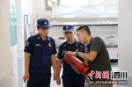 消防监督员现场检查校园灭火器是否在使用有效期。四川消防供图 - Sc.Chinanews.Com.Cn