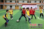 校园里孩子们正在踢足球。程欢悦摄 - Sc.Chinanews.Com.Cn