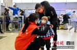 青年志愿者协助儿童旅客佩戴口罩。 邓文鑫 摄 - Sc.Chinanews.Com.Cn