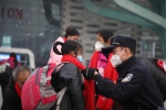 民警在成都东站东广场为一名务工人员子女整理围巾。 - Sc.Chinanews.Com.Cn