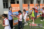 工作人员正在给学生们发放铁路安全资料。汪罡摄 - Sc.Chinanews.Com.Cn